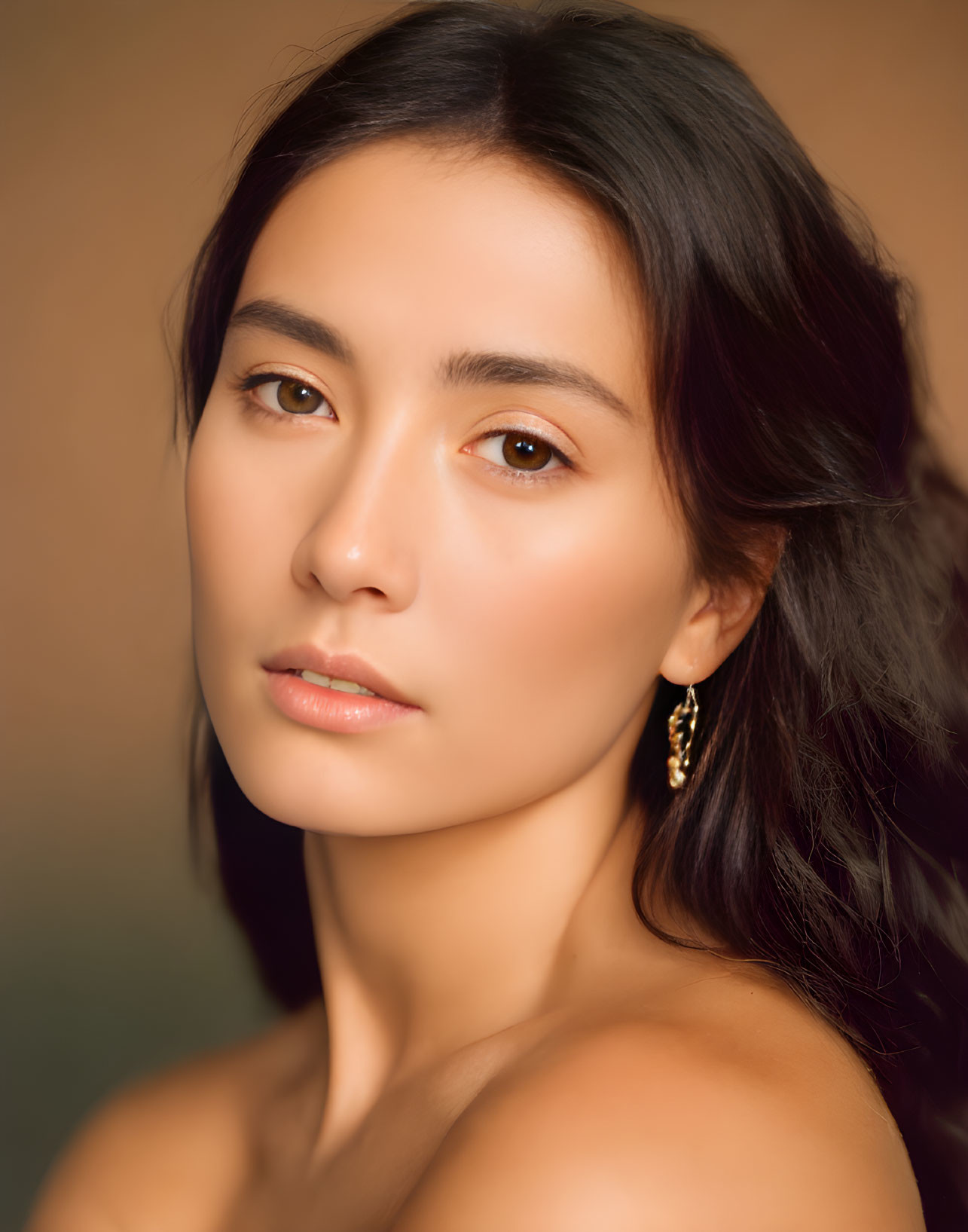 Portrait of Woman with Dark Hair and Bare Shoulder on Warm Background