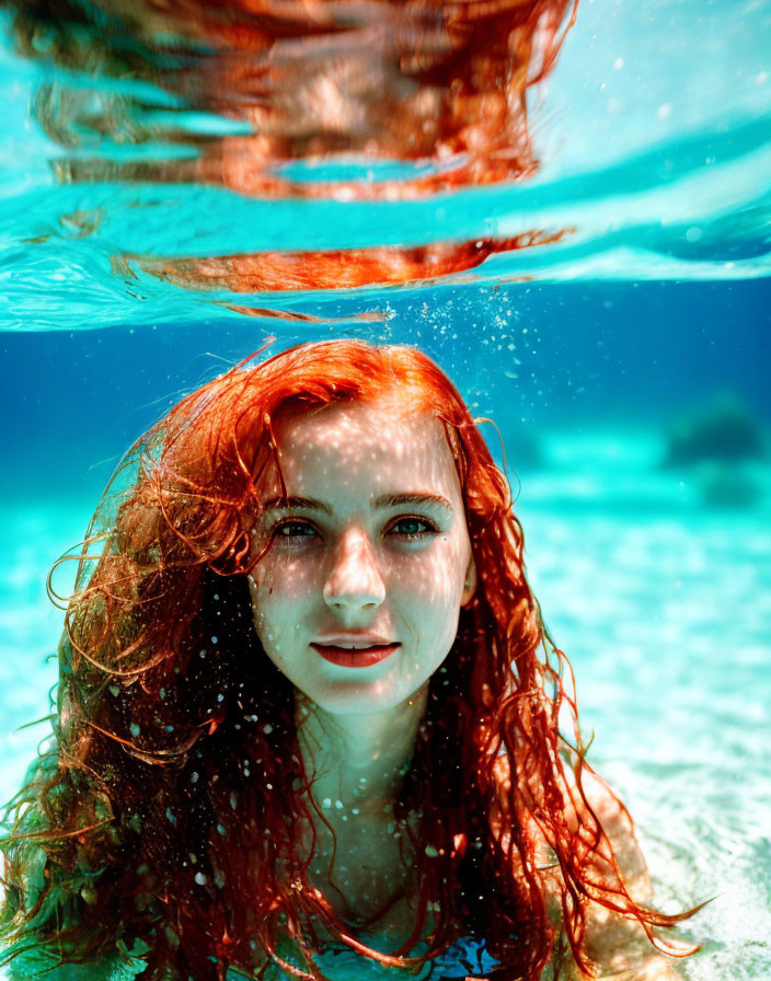 Red-haired woman emerges from clear blue water under sunbeams