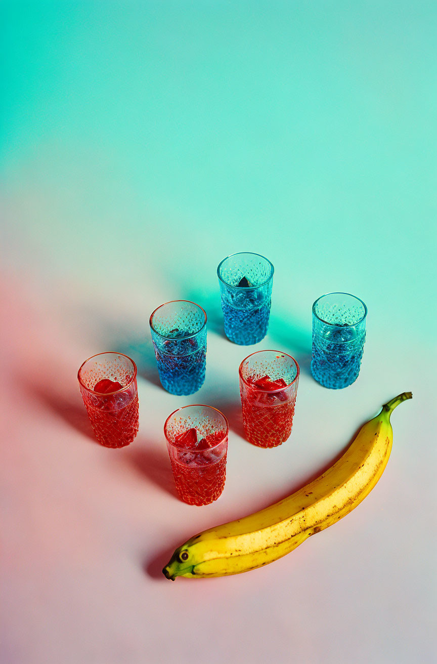 Colorful Glasses with Red and Blue Patterns Over Yellow Banana on Gradient Background