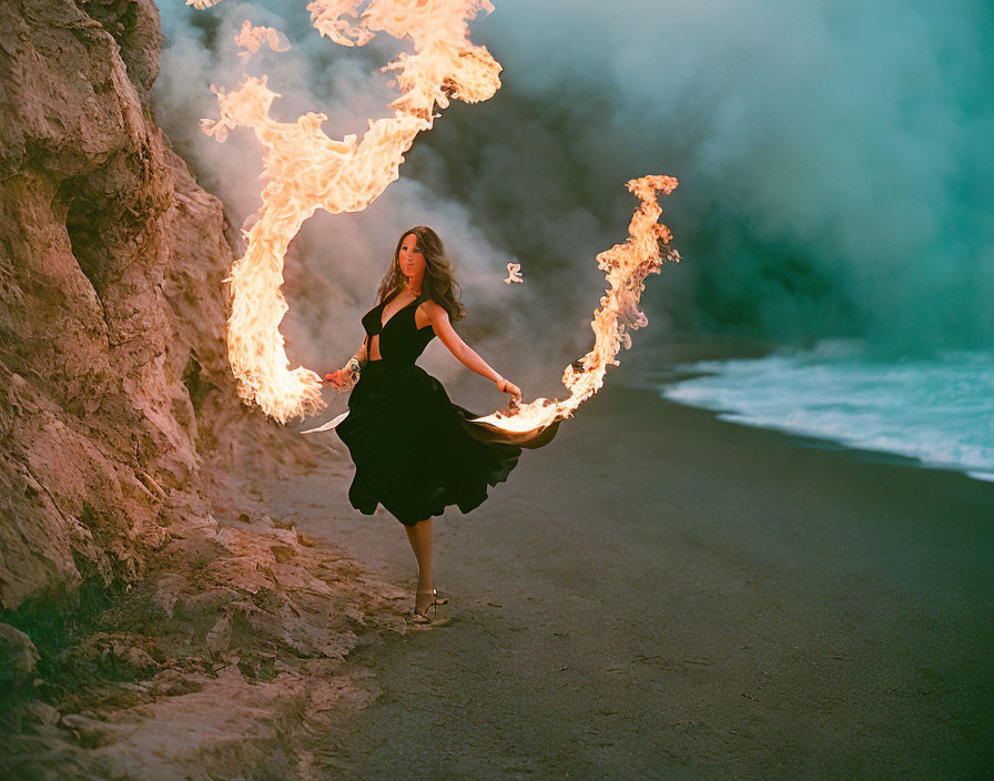 Woman in Black Dress Performs with Large Fire Props on Beach