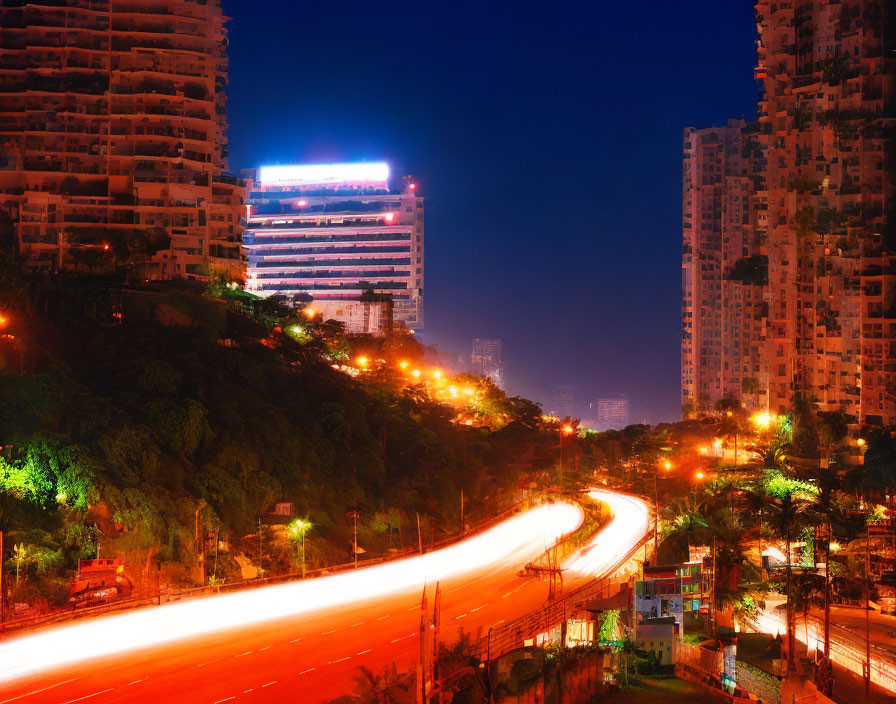 Urban night scene with glowing buildings, winding road, and light trails.