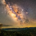 Sci-fi landscape with robotic insects over grassy field under starry sky