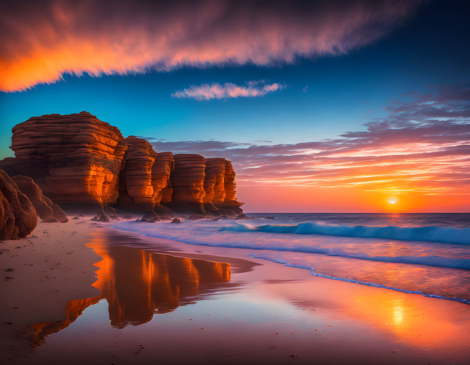 Colorful sunset sky over beach with cliffs and waves