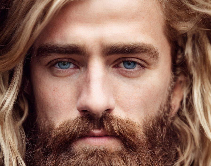 Portrait of man with long blonde wavy hair and piercing blue eyes