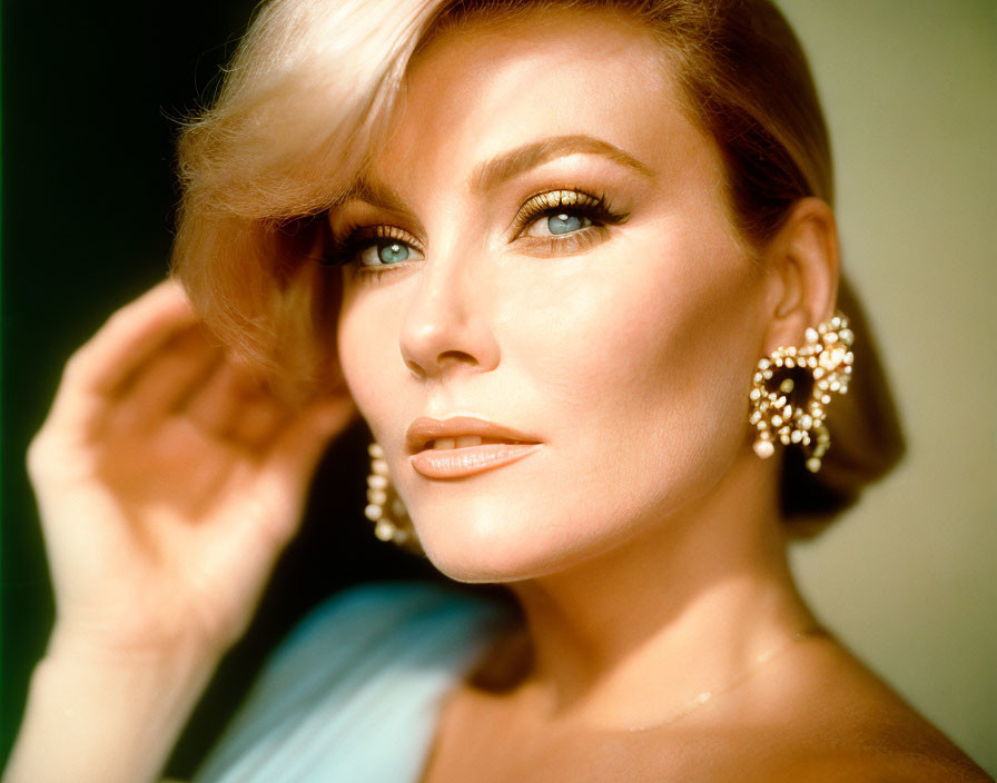 Blonde woman with dramatic makeup and sparkling earrings.