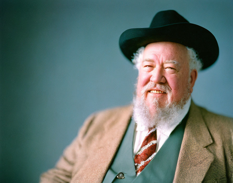 Elderly man in black hat and brown suit on blue background