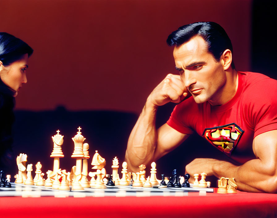 Man in Superman T-shirt playing chess with woman on red backdrop