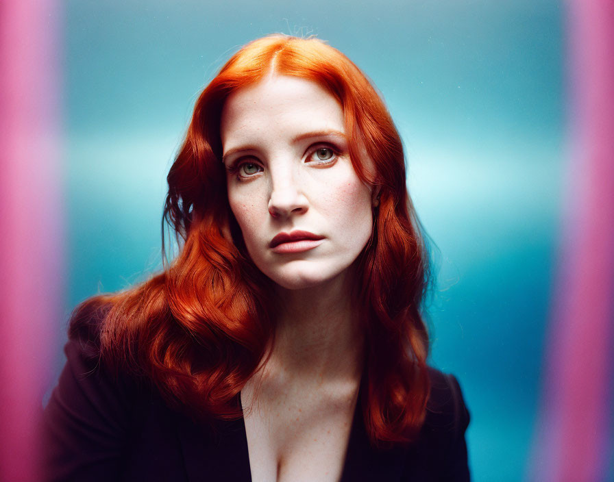 Striking red-haired woman gazes against blue background