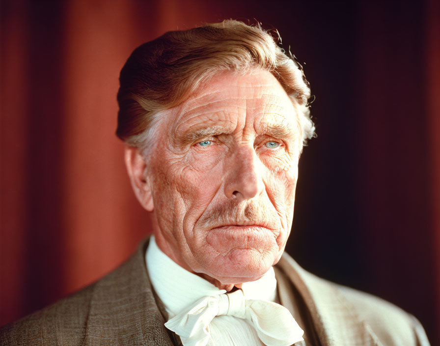 Elderly man in suit and ascot with intense blue eyes