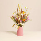 Vibrant bouquet of white, orange, and red flowers in pink vase