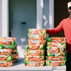 Cheerful delivery person with stacked takeout containers in red outfit