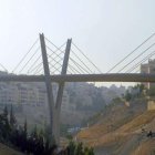 Suspension bridge with twin towers over city and hills under clear sky