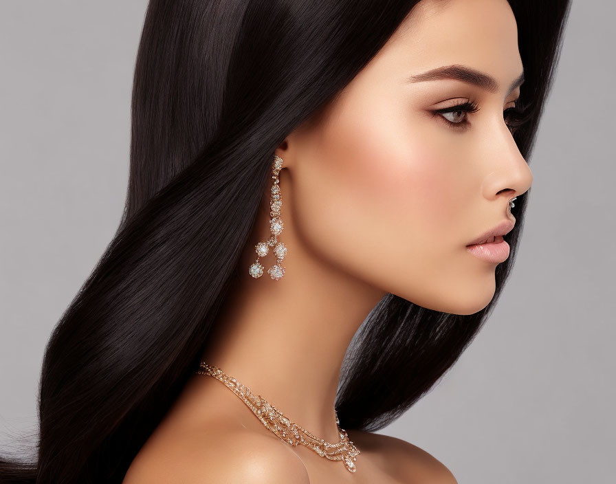 Profile View of Woman with Long Dark Hair and Sparkling Accessories on Gray Background