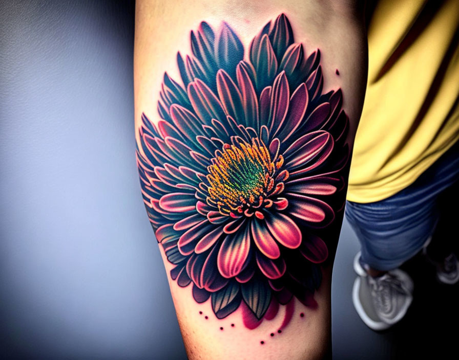 Vibrant blooming flower tattoo in pink, blue, and orange on arm