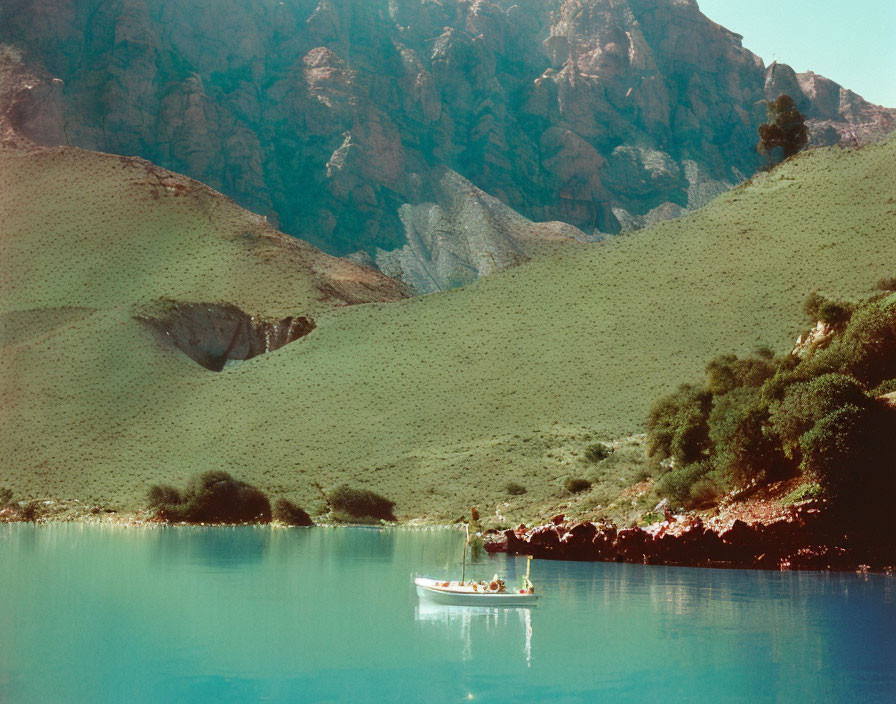 Tranquil lake scene with boat, green hills, and mountains