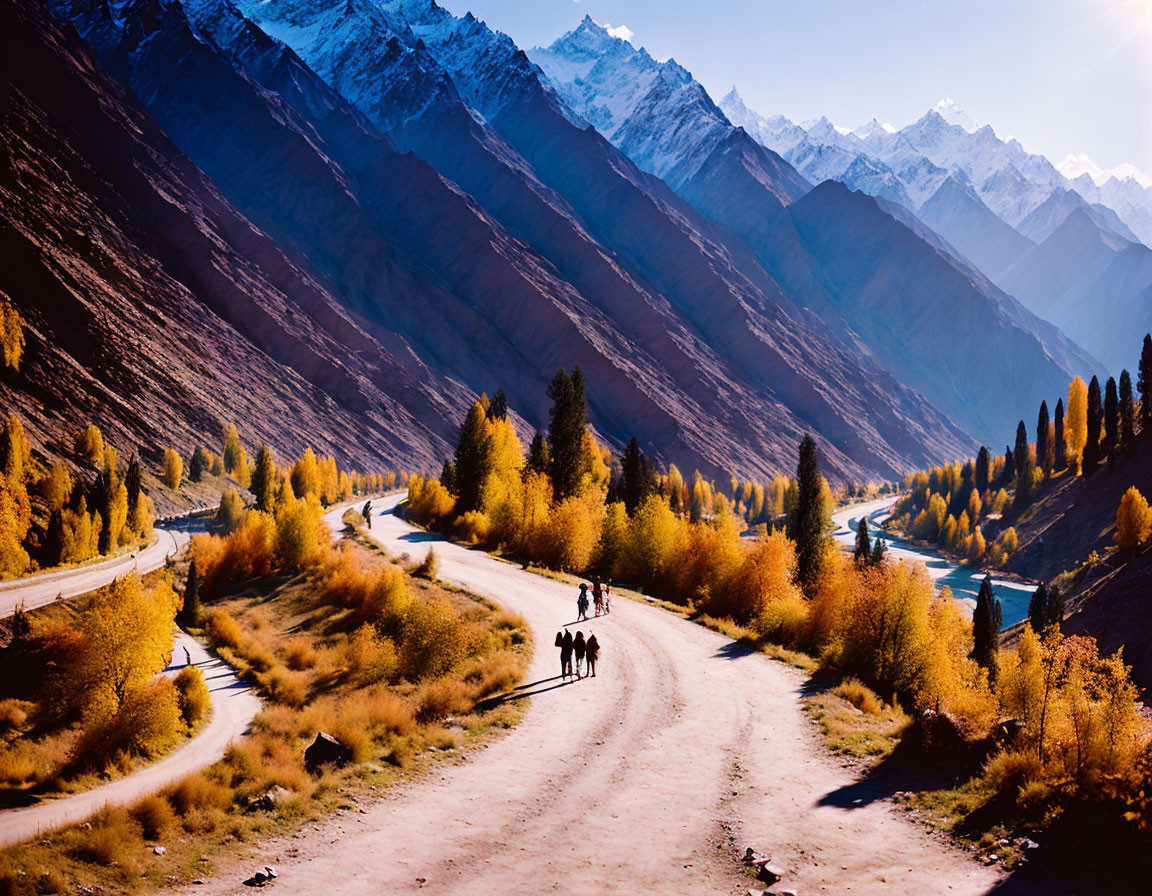 Scenic autumn valley with snow-capped mountains and horseback riders