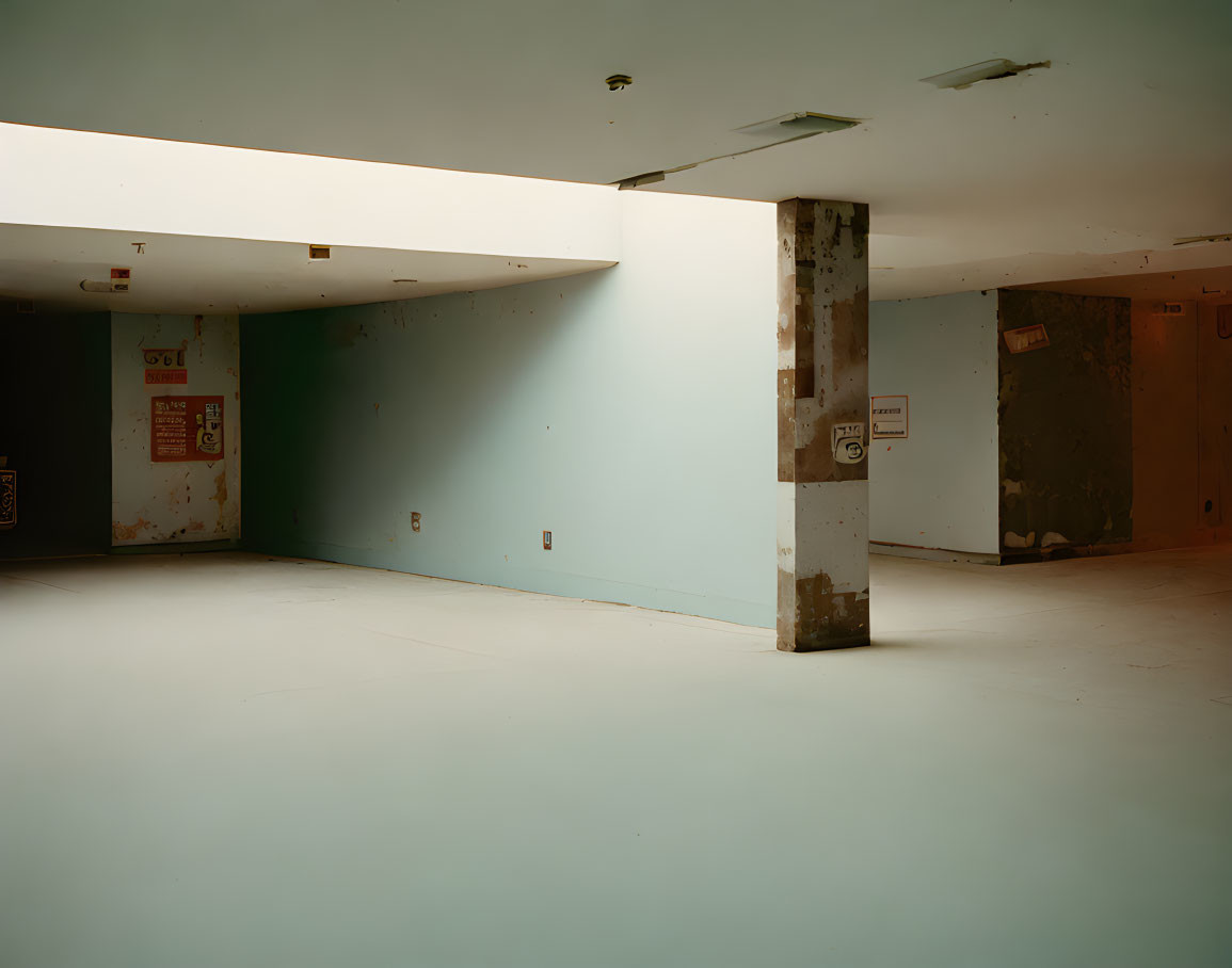 Desolate room with worn column, chipped walls, and single door.