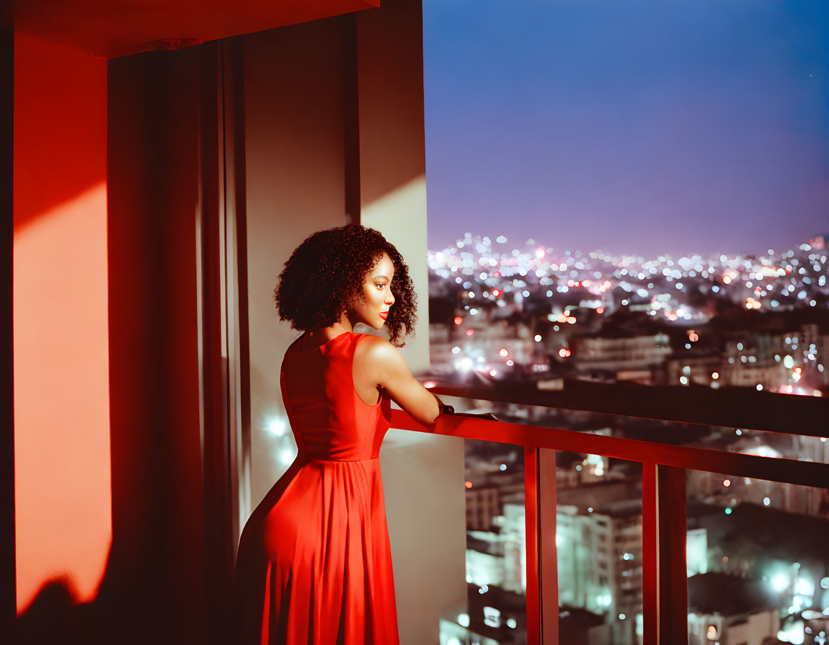 Woman in Red Dress on Balcony Overlooking City at Night