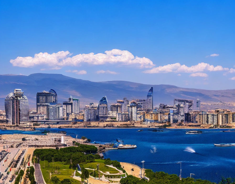 Modern city skyline with skyscrapers along coastline under blue sky.