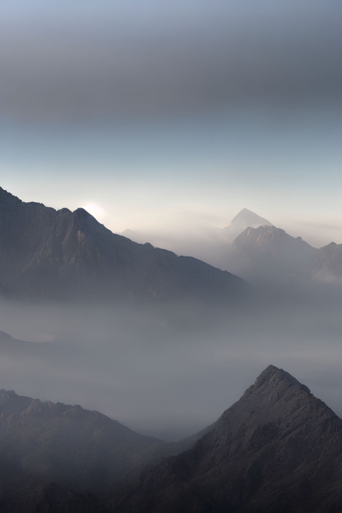 Sunlit misty mountain ranges under soft clouds