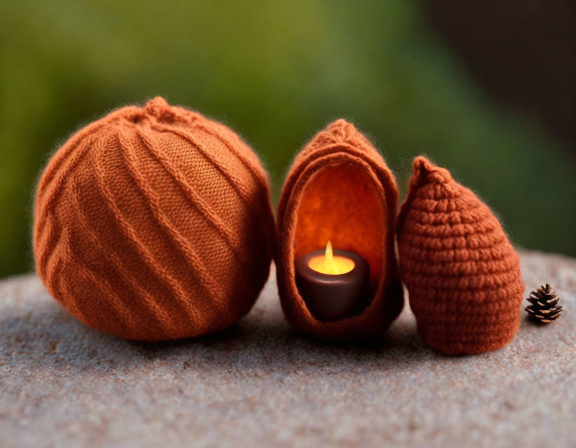 Woolen pumpkin yarn balls with candle on stone surface