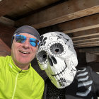 Surrealist image: person in hat with colorful skull face paint beside large skull in cave with turbulent