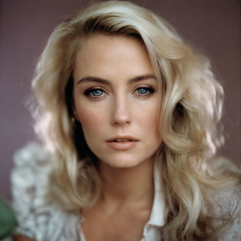 Portrait of woman with wavy blonde hair and blue eyes in white blouse