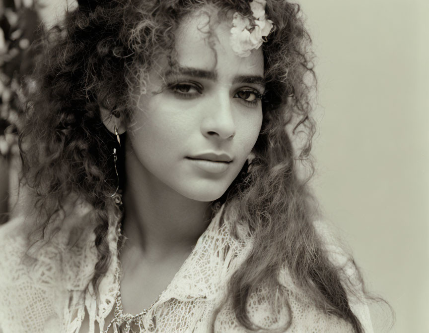 Sepia-Toned Portrait of Young Woman with Curly Hair and Flower in Vintage Attire