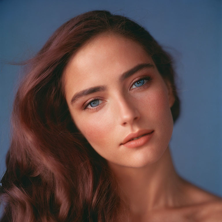 Portrait of Woman with Brown Hair and Blue Eyes on Blue Background