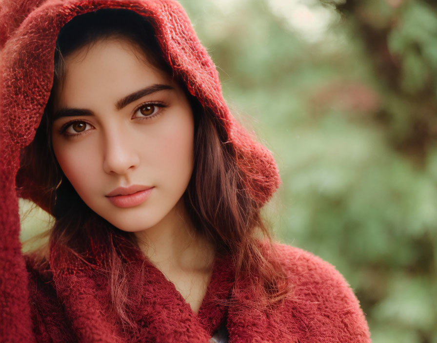 Red hooded figure in soft focus green foliage background