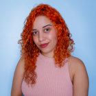 Vibrant red-haired woman with golden crown and pink lipstick on blue background