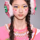 Portrait of woman with striking blue eyes and floral headpiece, intricate braids, colorful outfit