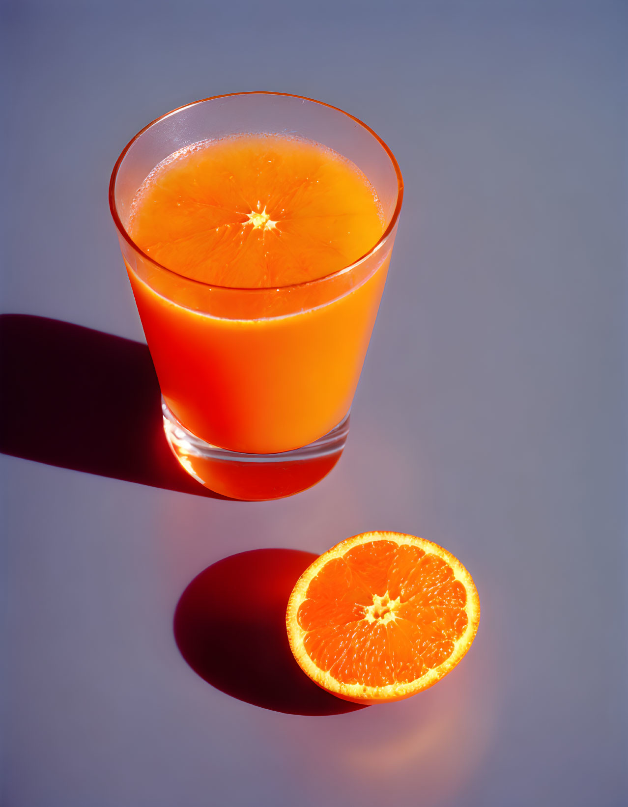 Fresh orange juice with vibrant orange slice on light surface