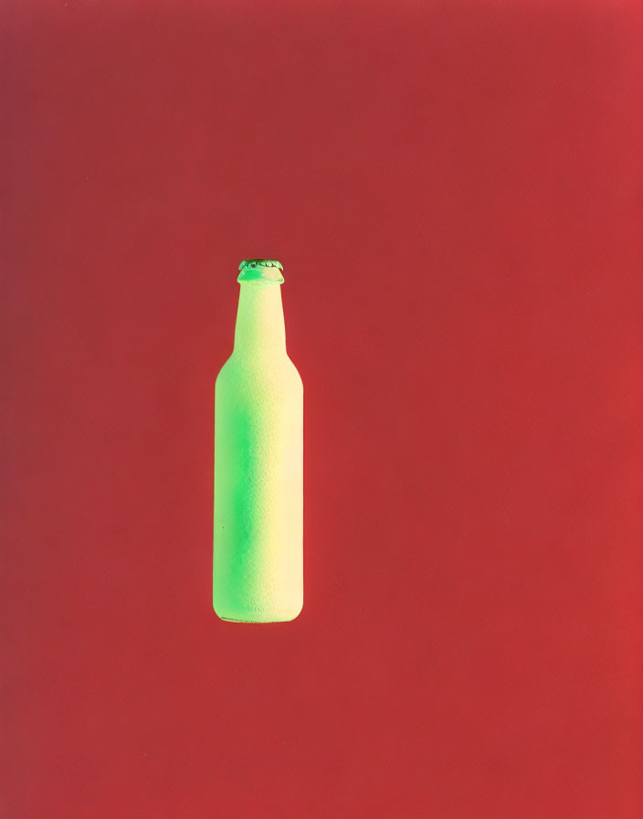 Green Glass Bottle Against Solid Red Background: Color Contrast Displayed