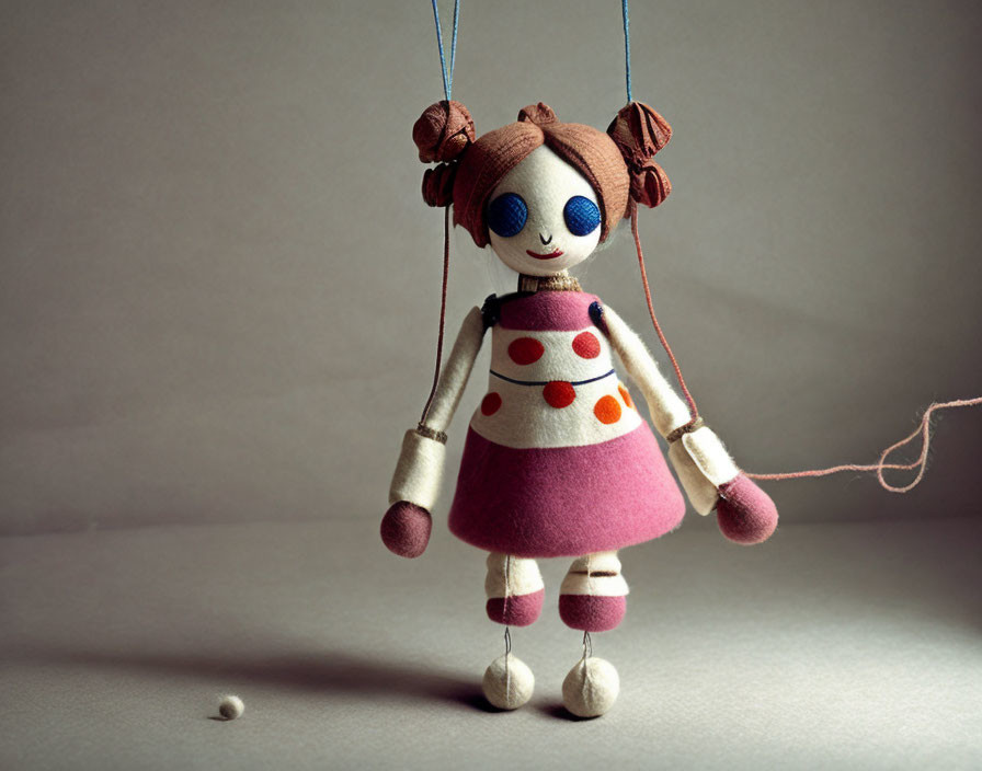 Handmade puppet with button eyes and pigtails in pink polka-dotted dress