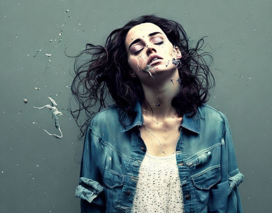 Woman in denim jacket splattered with white liquid on gray background