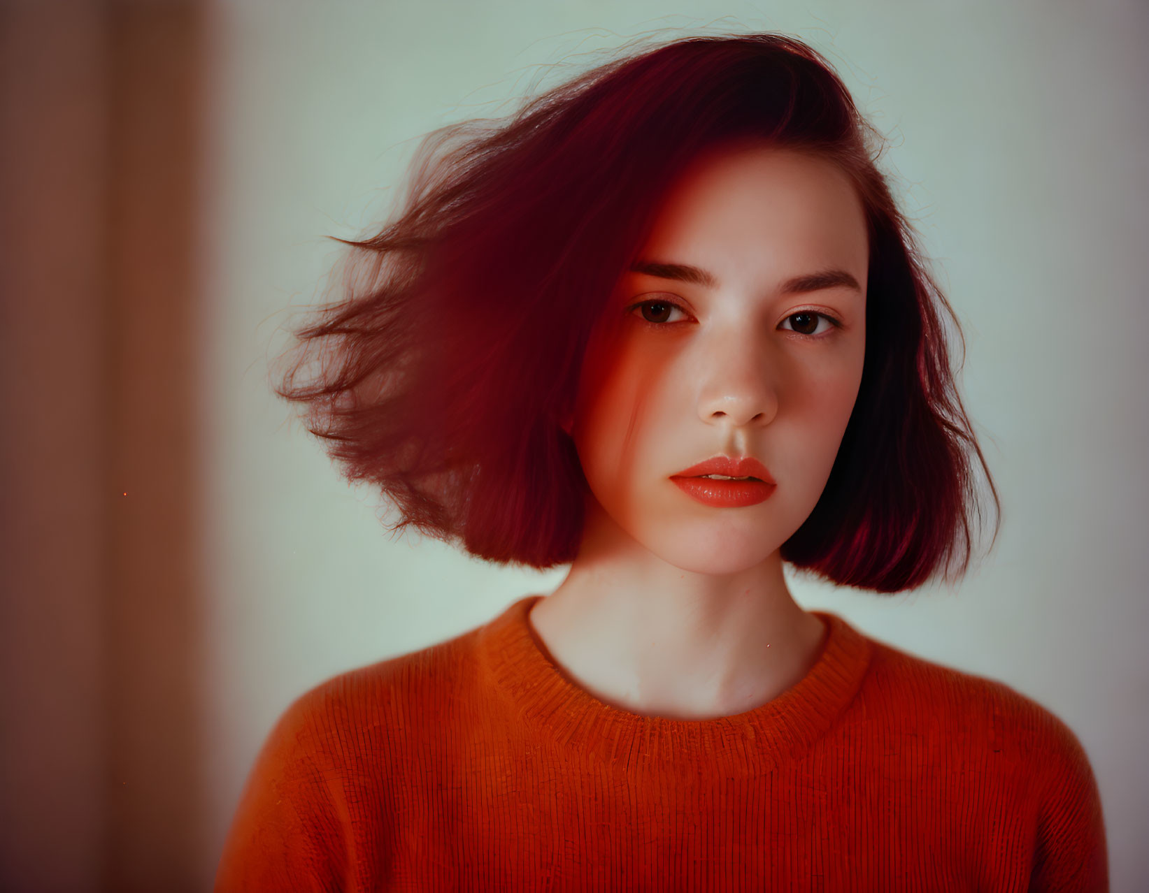 Auburn-Haired Woman in Orange Sweater with Serious Expression