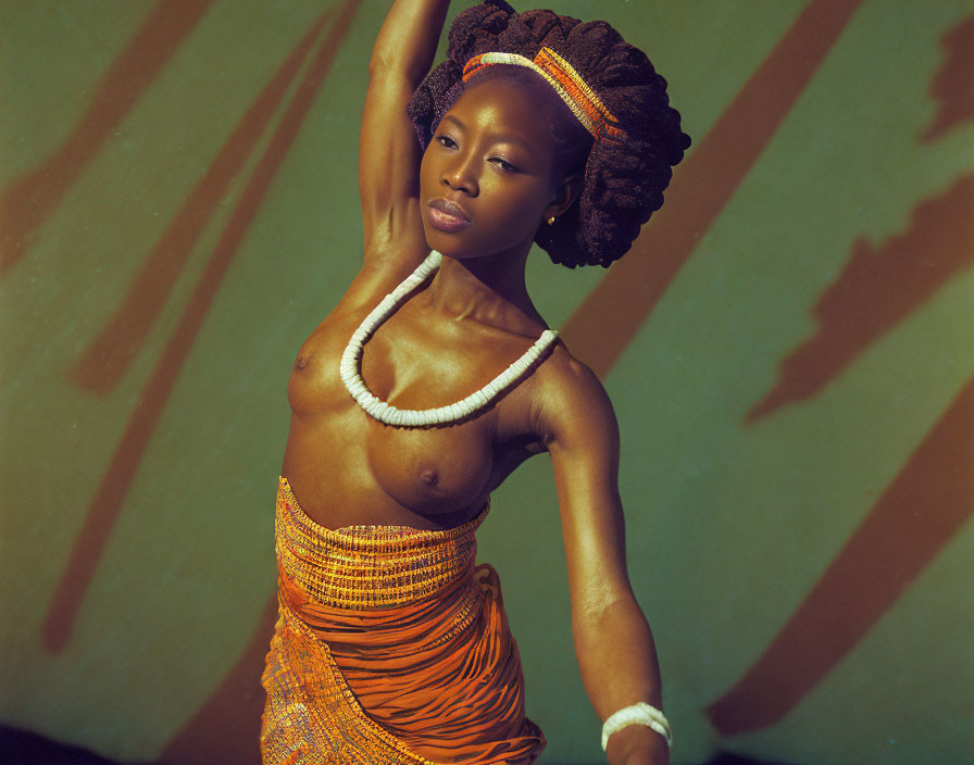 Stylish woman in orange outfit with raised arm on shadow-patterned background