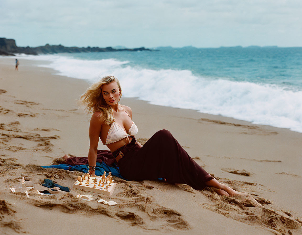 Woman on sandy beach with chessboard, ocean, cloudy sky