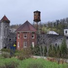 Fantasy countryside landscape with stone buildings, turrets, and gardens under cloudy sky