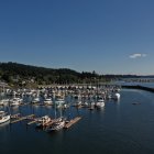 Vibrant harbor scene at dusk: lit buildings, blooming flowers, boats, lighthouse,