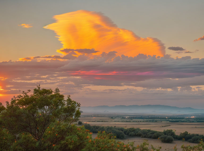 Orange-hued cloud dominates tranquil sunset landscape