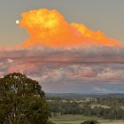 Orange-hued cloud dominates tranquil sunset landscape