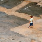 Child in overalls on fish path in surreal landscape with boats and swimming fish