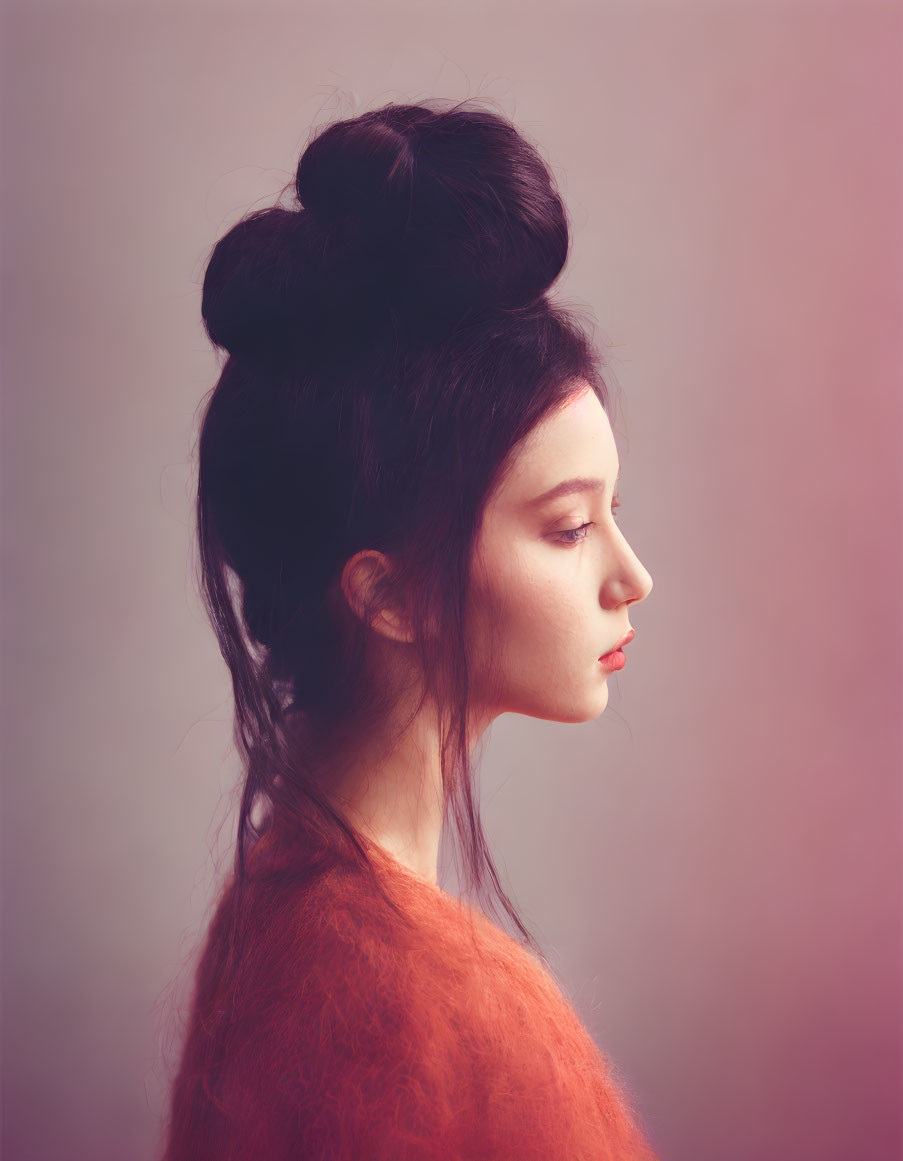 Woman with elegant bun hairstyle in orange sweater on pink background