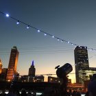 Fantastical cityscape at dusk with illuminated towers and gondolas on suspended track