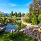 Manicured garden with pond, colorful plants, two houses, blue sky