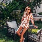 Fashionable woman in floral outfit on stone steps with sunglasses and red bag