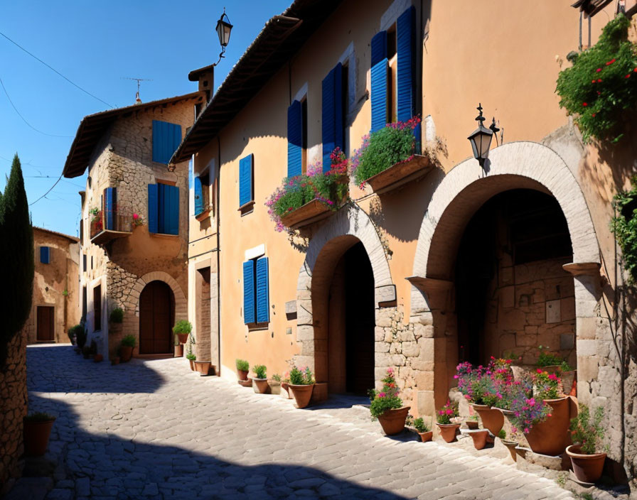 Picturesque cobblestone street in European village with terracotta-roofed houses and colorful flowers