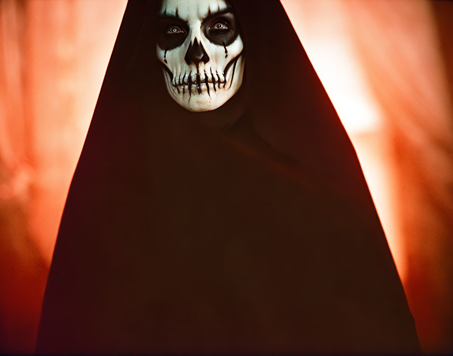 Skeleton-faced person in dark cloak on red background.